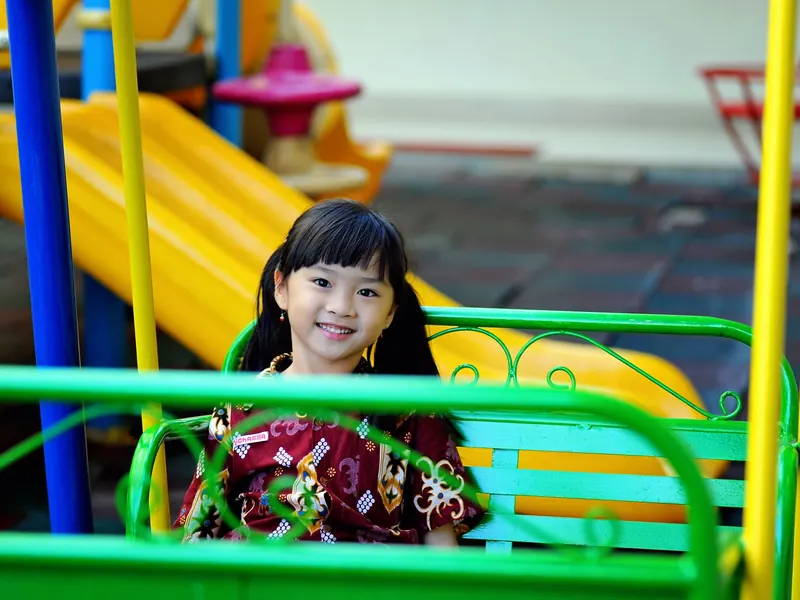 Bé gái cười tươi ở sân chơi cầu trượt