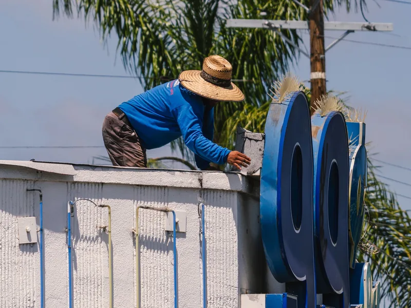 Thợ đang vệ sinh bảng hiệu lớn trên mái nhà