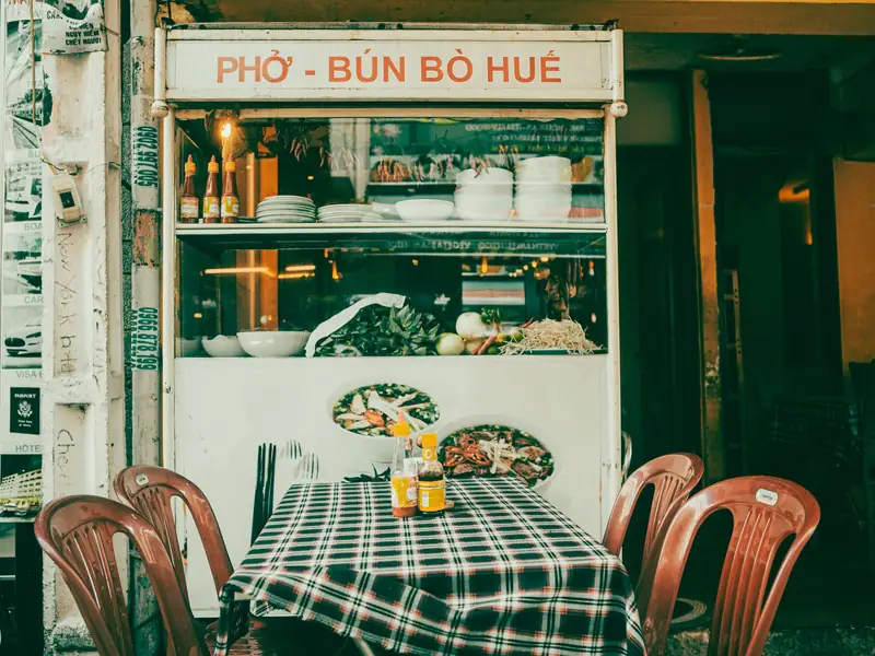 Mặt tiền quán với bàn ghế gỗ và khăn trải bàn caro