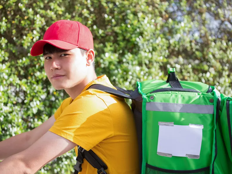 Shipper đội mũ đỏ đeo thùng giao hàng màu xanh