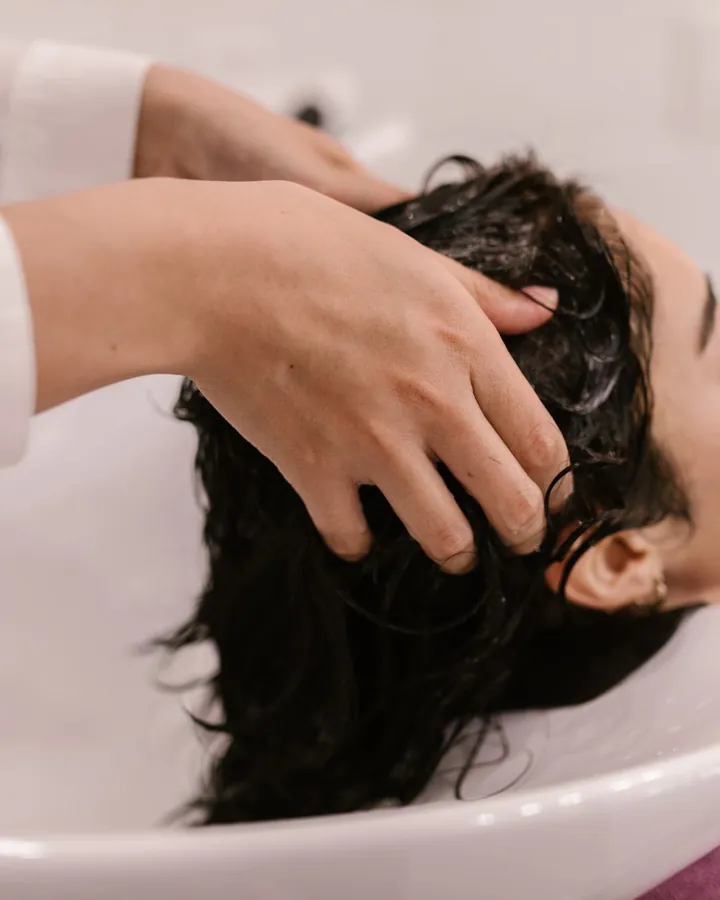 Kỹ thuật viên gội đầu cho khách tại bồn gội