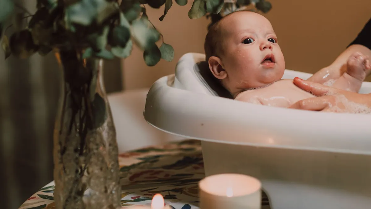 Em bé ngồi trong bồn tắm cạnh cây xanh