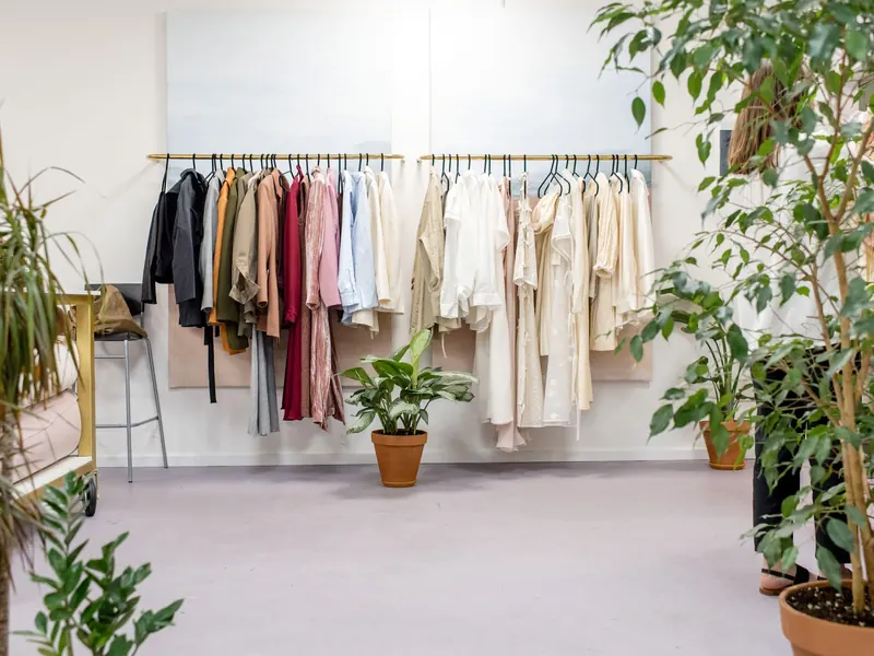 Showroom sáng với giá treo đồ và cây xanh